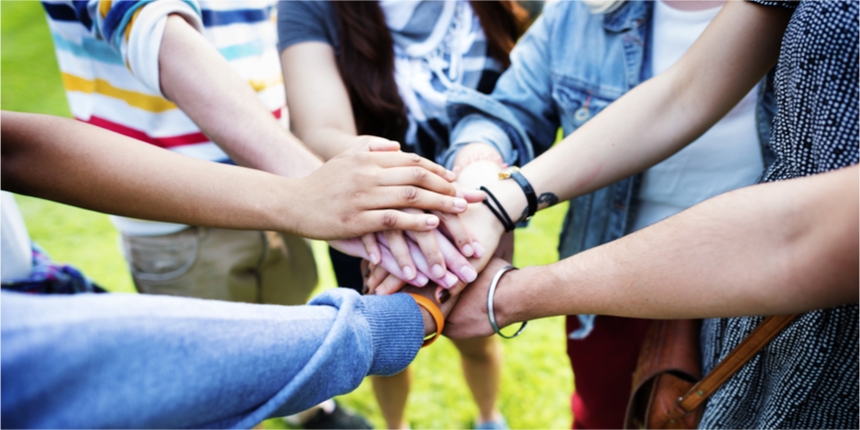 Young people holding hands in a circle